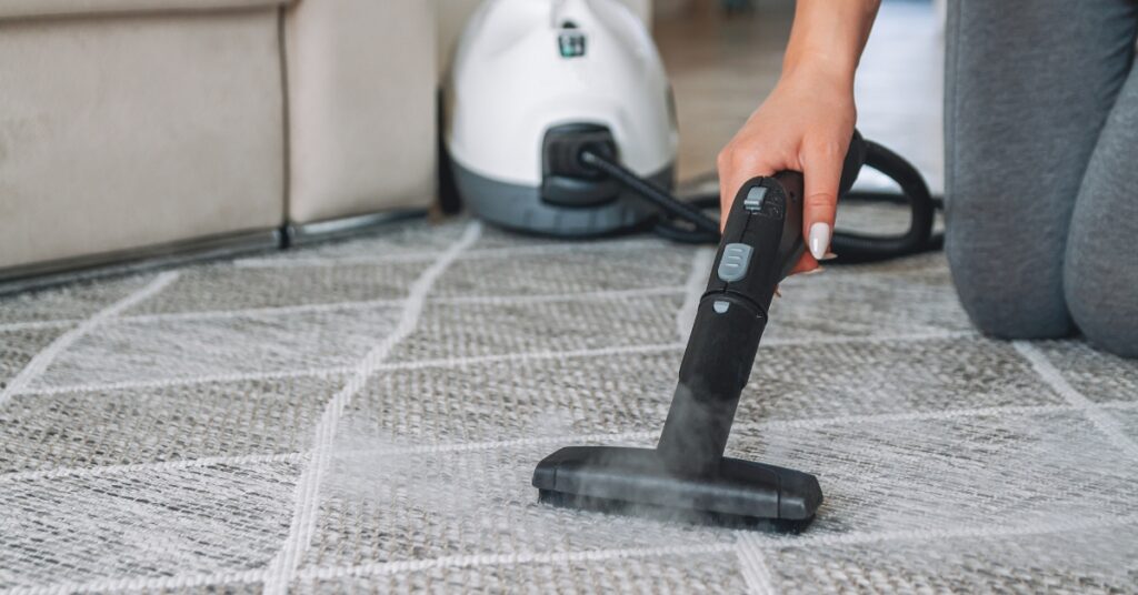 Woman cleaning the carpet with a steam cleaner